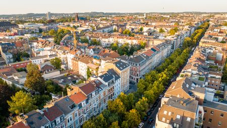 Bebautes Viertel mit einer Baumallee in der Abendsonne aus der Vogelperspektive.