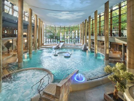 Innenbereich und Hauptbecken der Carolus Thermen umrandet von hohen Säulen und einer Glasfront.