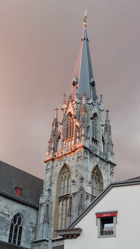Grauer Kirchturm in der Abendsonne.