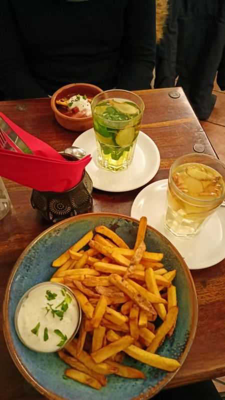 Auf einem Tisch steht ein frischer Pfefferminztee und ein Teller mit Pommes Frites mit einer Schale Mayonnaise.