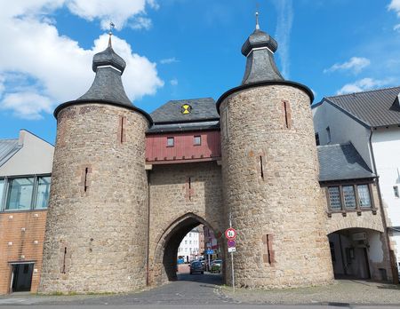 Torbogen zwischen zwei steinernen Türmen unter blauem Himmel.