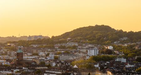Luftbild von der Aachener Innenstadt und dem Lousberg im Hintergrund bei Sonnenuntergang.
